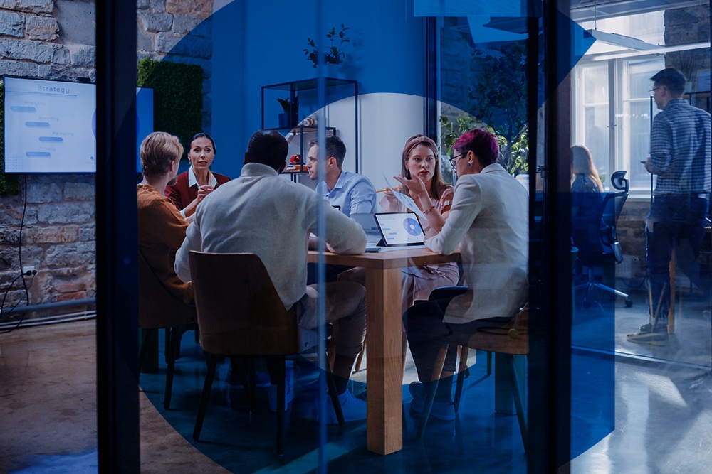 Growth Hacking - imagem de várias pessoa em uma sala de reunião, com paredes de vidro, todos sentados em volta da mesa